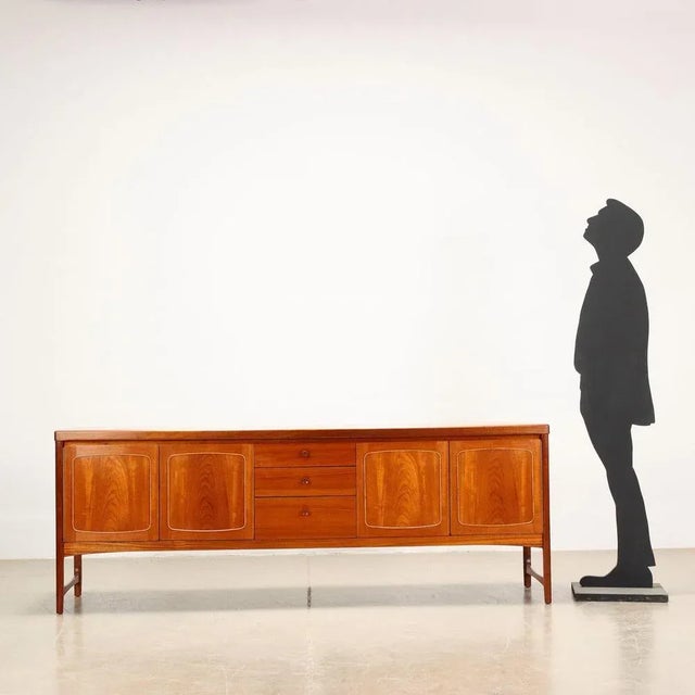 Sideboard in teak veneered wood with double hinged doors and exposed drawers. This piece is attributed to the mentioned...