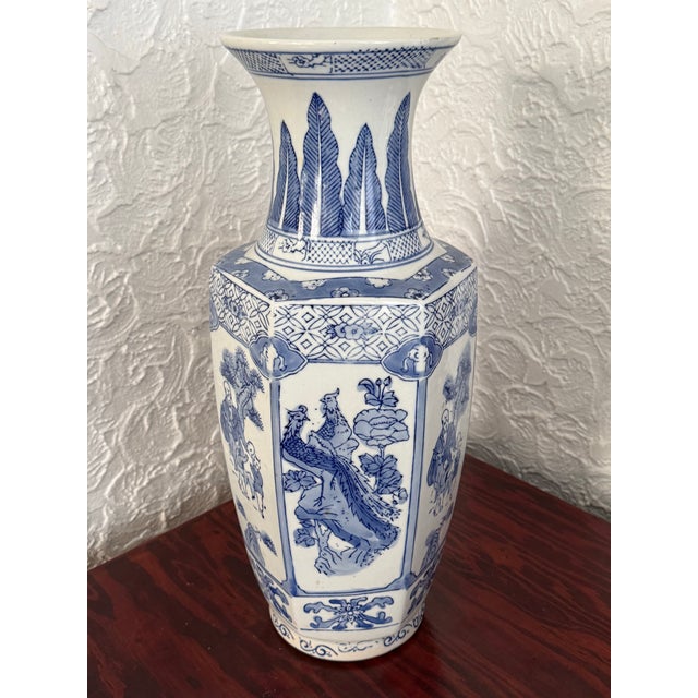 Large blue and white porcelain vase with a faceted body and tall flared neck. The panels show alternate between figures...