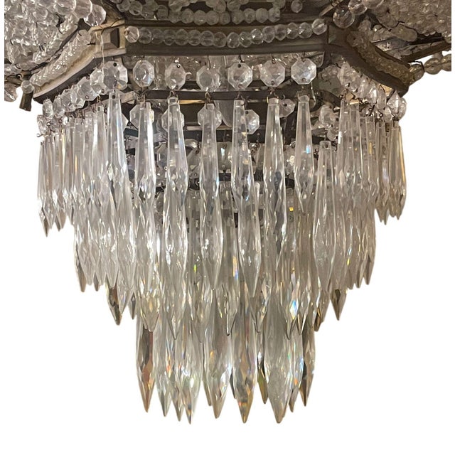 Impressive 19th century French Empire chandelier featuring a gilt bronze frame with cascading crystal bead swags and...