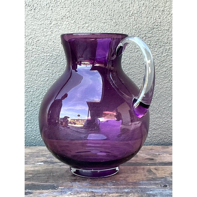 Pour a glass of vibrant sophistication with this stunning vintage hand-blown art glass pitcher. The vessel features a...