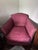 Victorian-era sofa and matching armchair featuring graceful carved wood frames, cabriole-style legs, and rich rose-colored...