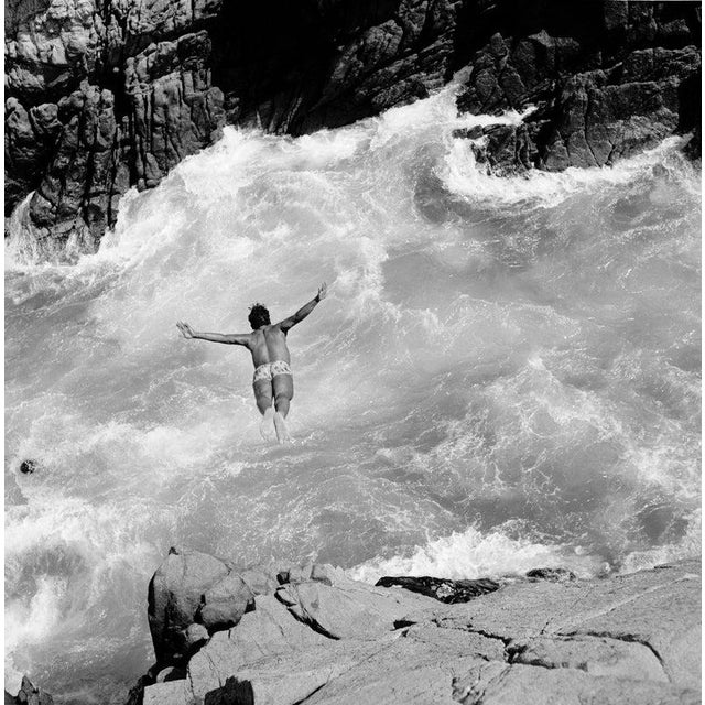 Pacific Diver Circa 1950: Swimmer diving into rough water lashing against rocky cliffs at Acapulco, the Riviera of Mexico....