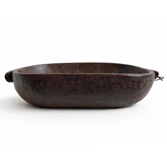 This large hand-carved wooden bowl from Burundi reflects the enduring woodworking traditions of rural communities such as...