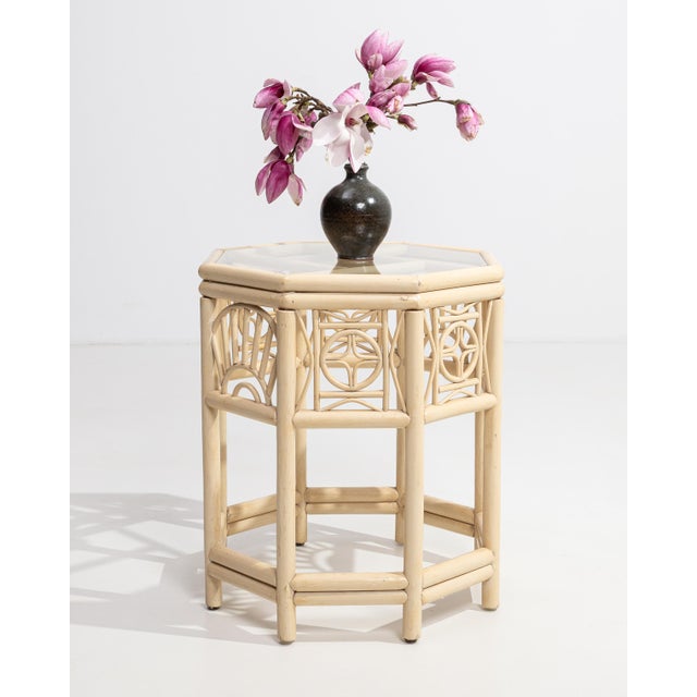 A decorative side table influenced by Chinoiserie design, featuring delicate detailing and a protective glass top. The...