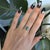 A natural indicolite tourmaline glows in cool blue-green at the center of this baguette ring, flanked by delicate pink...