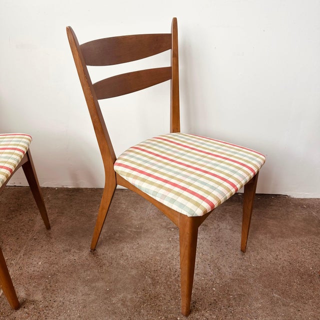 Set of 4 mid-century dining chairs in a mid to light tone brown with plaid upholstered cushions. Retains original...
