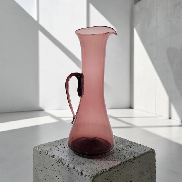 This hand-blown Blenko amethyst glass pitcher, Model #579, was designed by Wayne Husted during the 1950s. Produced in the...