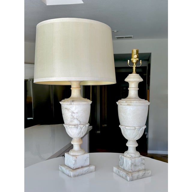 Pair of large scale finely crafted hand carved neoclassical style urn form alabaster table lamps. Expertly crafted with...