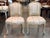 A small pair of French side chairs in an old pale green painted finish, each with a shaped cartouche back crested by a...