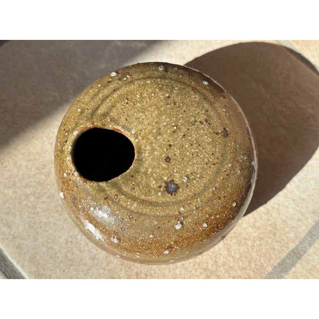 A handcrafted studio ceramic vase, deliberately "imperfect," rustic, yet precise in its execution, reflecting the unique...