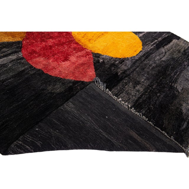 Beautiful Moroccan hand-knotted wool rug with a charcoal field and fringes. This Modern rug has goldenrod and red accent...