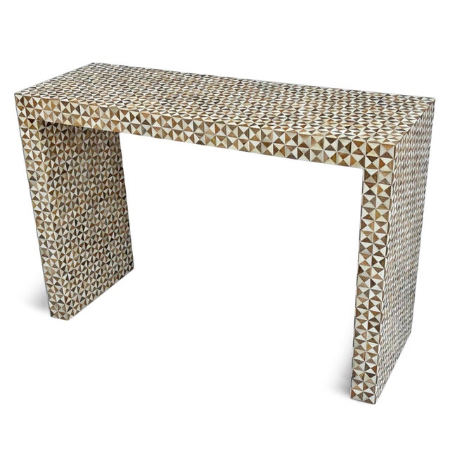 Handcrafted console table from India. Clean waterfall silhouette wrapped in a striking geometric inlay pattern, creating a...