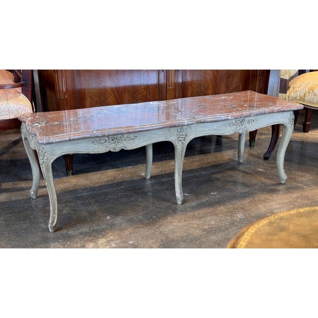 Rectangular painted coffee table with shaped marble top above a carved apron centered with floral motifs. Raised on four...