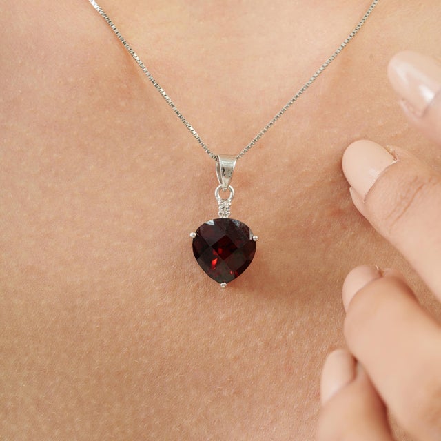 The Carat&Her Crimson Ember Pendant features a striking 4.93-carat trillion-cut garnet with a deep crimson hue and...