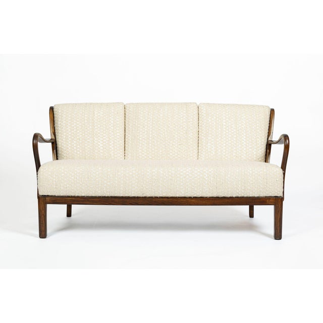 This vintage mid century Danish modern three-seat sofa was produced circa 1960 and features a beautifully crafted solid...