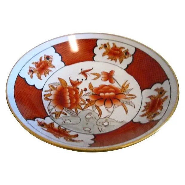 Porcelain polished brass-encased bowl in a vibrant hand-painted floral-motif in shades of coral, tan, black, and white....