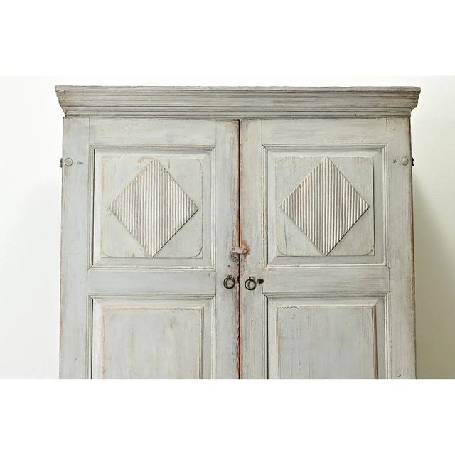 A painted Swedish Gustavian armoire from the late 1700’s. This solid pine cabinet has its original light gray-blue paint...
