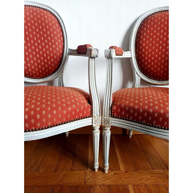 Pair of Louis XVI style armchairs in molded wood, painted white and upholstered in salmon jacquard fabric with orange...