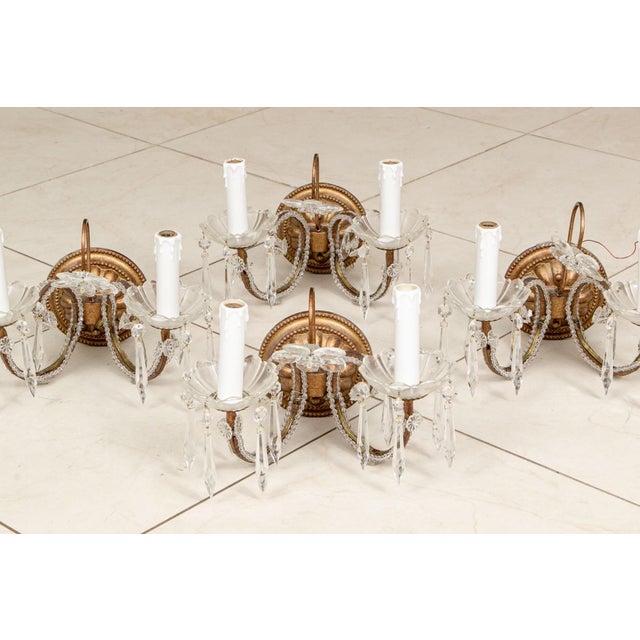 Set of four French style crystal and bronze finished two-arm wall sconces with ornate backplates with beaded detailing,...