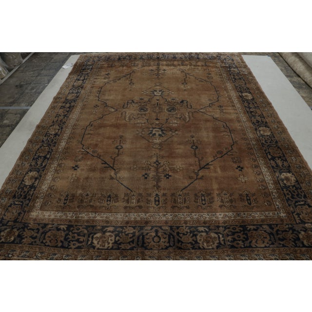 Hand-knotted in wool, this 8x11 antique Turkish Isparta rug, circa 1920-1930, enjoys rich brown and navy blue tones in...