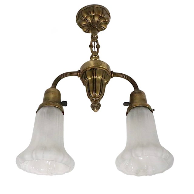 Antique early electric two light pendant fixture featuring a brass frame with two glass shades. The chandelier is in very...