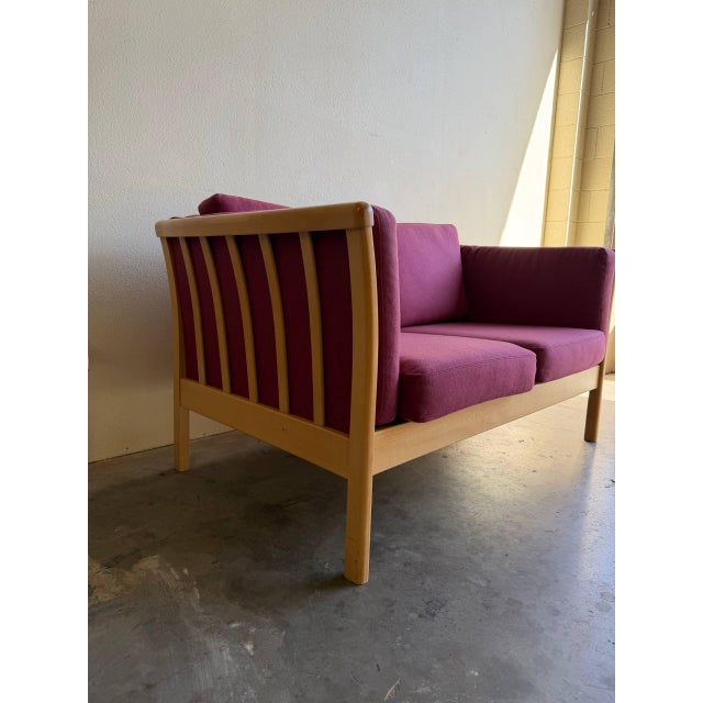 Danish Mid-Century Modern loveseat by Stouby, featuring sculptural solid beechwood framing and rich plum-purple...