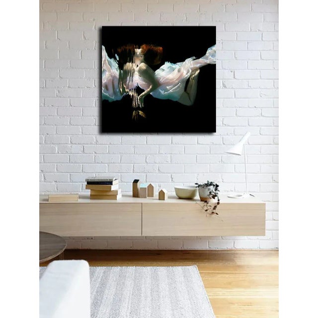 "feather" is and underwater female swimmer with red hair, dropping a yellow feather. C print on fuji pearl,...