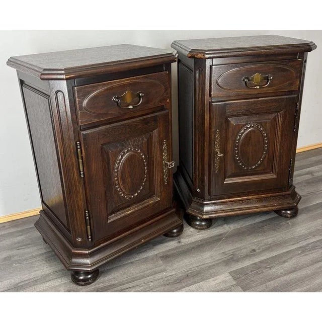 A striking pair of Vintage French bedside cabinets crafted from dark-stained oak, featuring rich panelled detailing and...