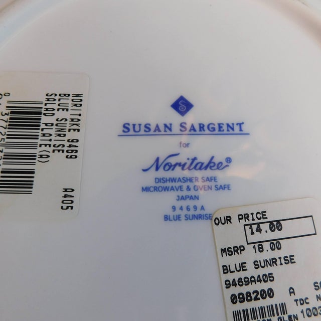 This is one Noritake Plate in Blue Sunrise by Susan Sargent. The plate is white with a blue flower center and blue details...