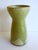 A vase with a tired olive green color, unusual for meisel. A thick, glossy glaze forms drops on the base. A matte corn...