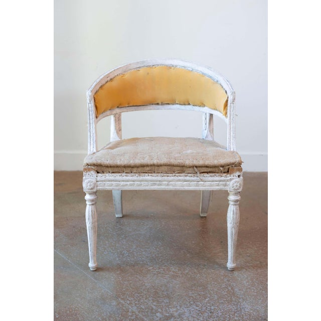 This Swedish Gustavian-style painted wood tub chair dates to the late 19th century and showcases curving lines, carved...