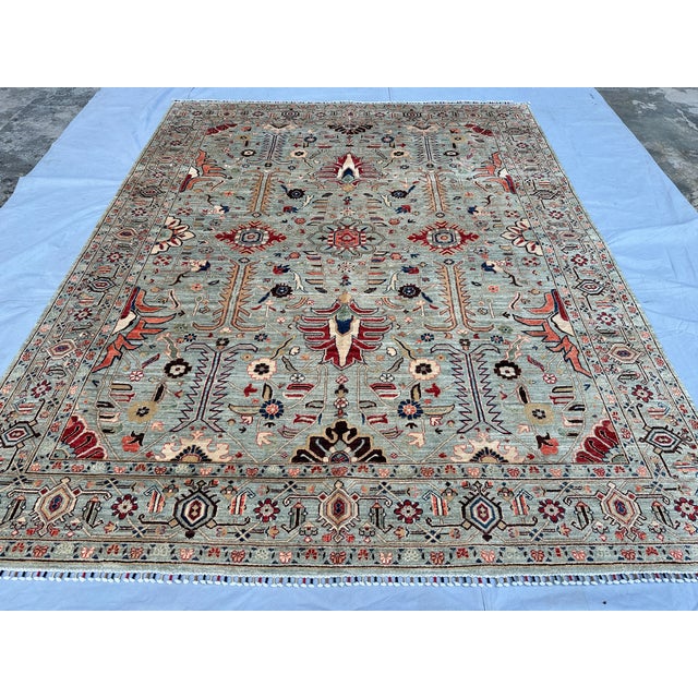 This exquisite hand-knotted wool area rug features a classic Serapi Heriz tribal design. The open center field showcases a...