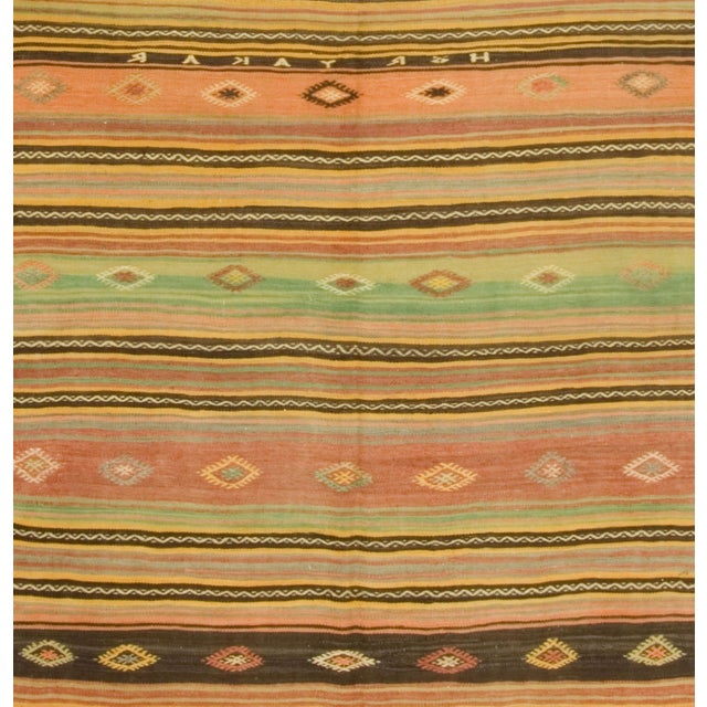 From around 1950, this Turkish Kilim features stripes in warm rose and pale green hues, complemented by geometric accent...