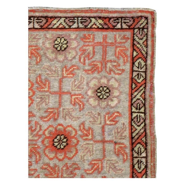 An antique East Turkestan Khotan 2' x 3' scatter/throw rug handmade during the early 20th century in shades of coral and...