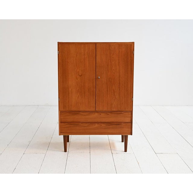 Teak cabinet with hinged doors, two lower drawers, and tapered legs. Scandinavian production, 1950s/1960s. Scandinavian...