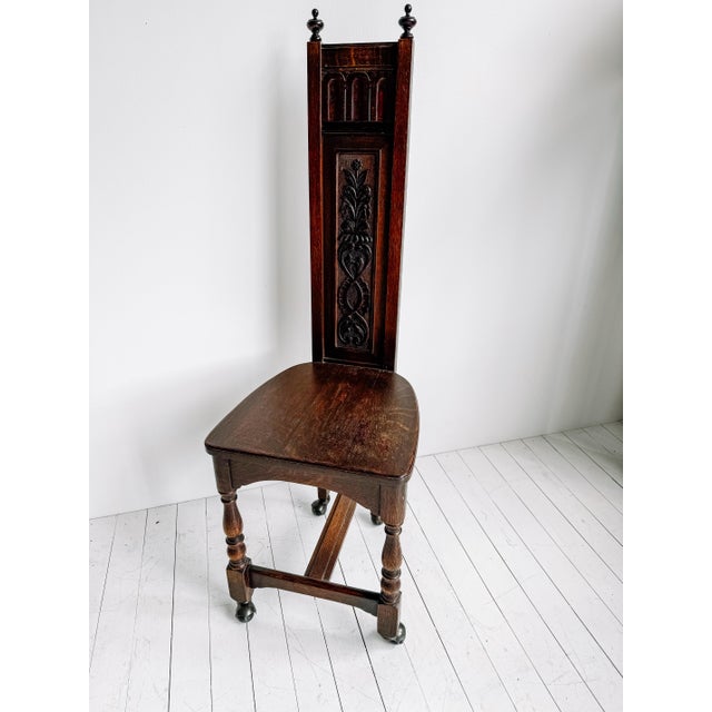 A late Victorian Gothic Revival hall chair crafted in solid oak, featuring a tall architectural back with carved tracery,...