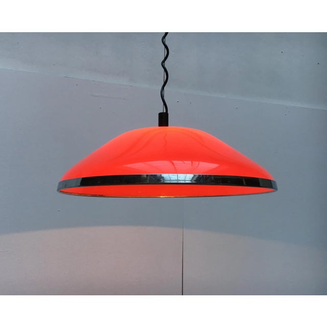 Very rare pendant lamp by Harvey Guzzini. The plastic screen shows the shape of a flat cone and is designed in red...