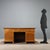 Art Deco desk in walnut and walnut burl. Three drawers in the lower section and side doors concealing three drawers. Brass...