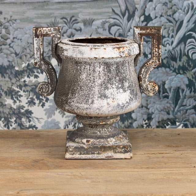 A handsome pair of iron urns with a beautiful, aged patina. Circa 1820. There is a hole in the bottom of each urn.