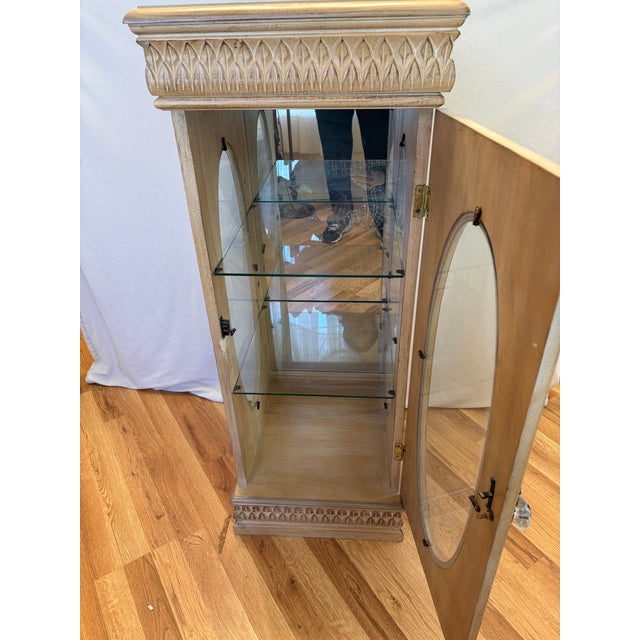 This 1980's Ethan Allen style blonde pier-curio cabinet with hand crafted wood details and two glass shelves is quite tall...