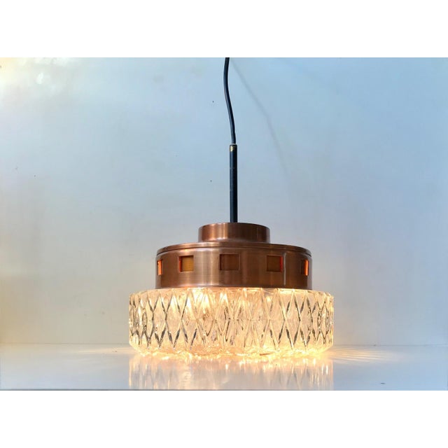 Crystal shaded pendant chandelier with partially perforated copper top. Manufactured by Orrefors in Sweden during the...