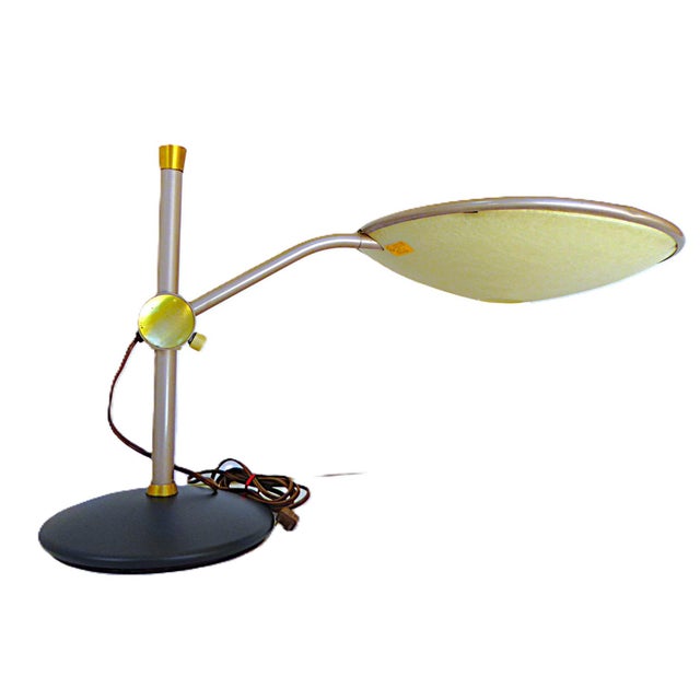 Dazor Lighting model #2008 Floating-Arm desk lamp. It has a shade with a Flying Saucer shape with a metal top and a...