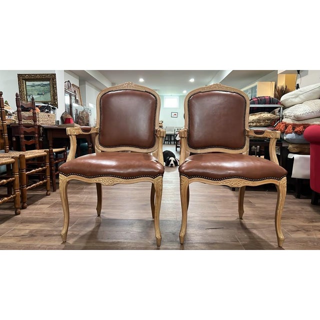 This pair of vintage French Provincial style armchairs features elegantly carved wooden frames, cabriole legs, nailhead...
