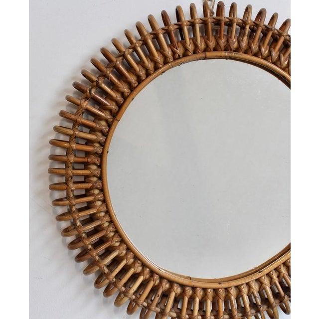 Mid-Century Italian rattan wall mirror (circa 1960s). This mirror has a complex weave of rattan in a series of horseshoe-...