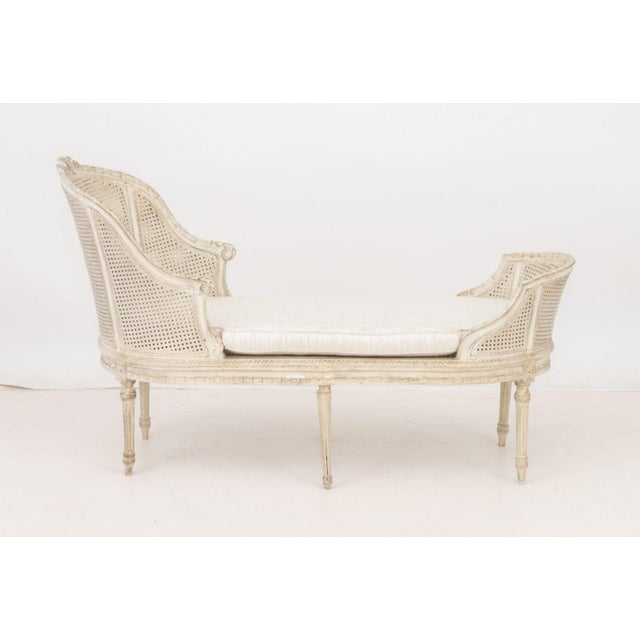 Louis XVI Style Caned Tete-a-Tete Chaise Longue, white painted wood, white silk upholstered cushion, on tapered fluted...