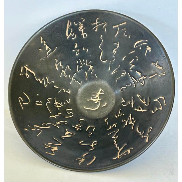 Artisan Chinese black-glazed (Heiyou) ceramic bowl featuring incised cursive calligraphy along the interior and rim. Black...