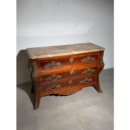 Elegant antique Louis XV style commode featuring a graceful bombe shape and a richly veined marble top. The cabinet is...