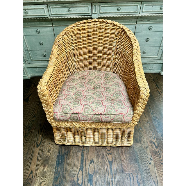 A charming vintage wicker club chair featuring an inviting barrel-form silhouette, generous proportions, and beautifully...