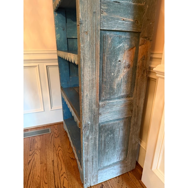 A wonderful antique primitive open cupboard featuring an exceptional timeworn blue painted finish and charming hand-cut...
