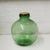 A green handblown decorative glass bottle with a 9cm bottle opening. The glass bottle features bubbles in the glass....